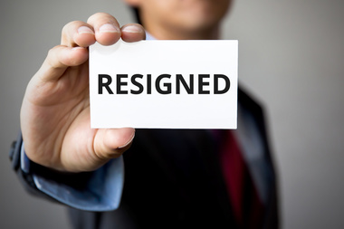 Businessman presenting 'RESIGNED' word on white card